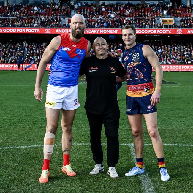 Boral's Nathan Hall on sports field in stadium with 2 professional AFL players
