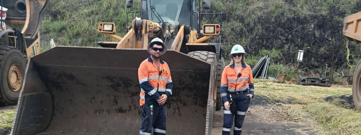 Hanna Moriconi and John West standing in front of an excavator