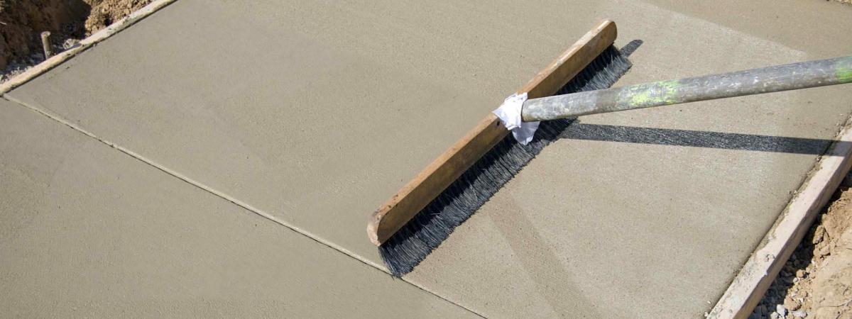 Concrete footpath being finished with a broom