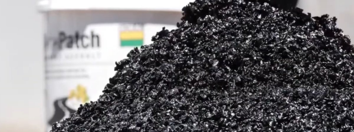 Closeup of asphalt in a pile with pail in the background.