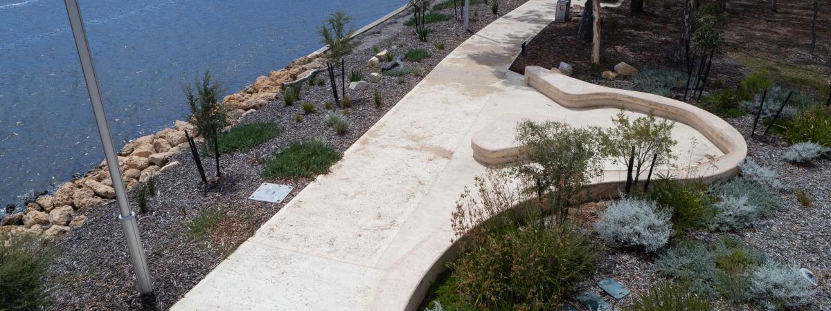 Coloured concrete pathway on Heirisson Island featuring Colori® Turmeric finish, connecting landscaped public spaces near Boorloo Bridge in Perth