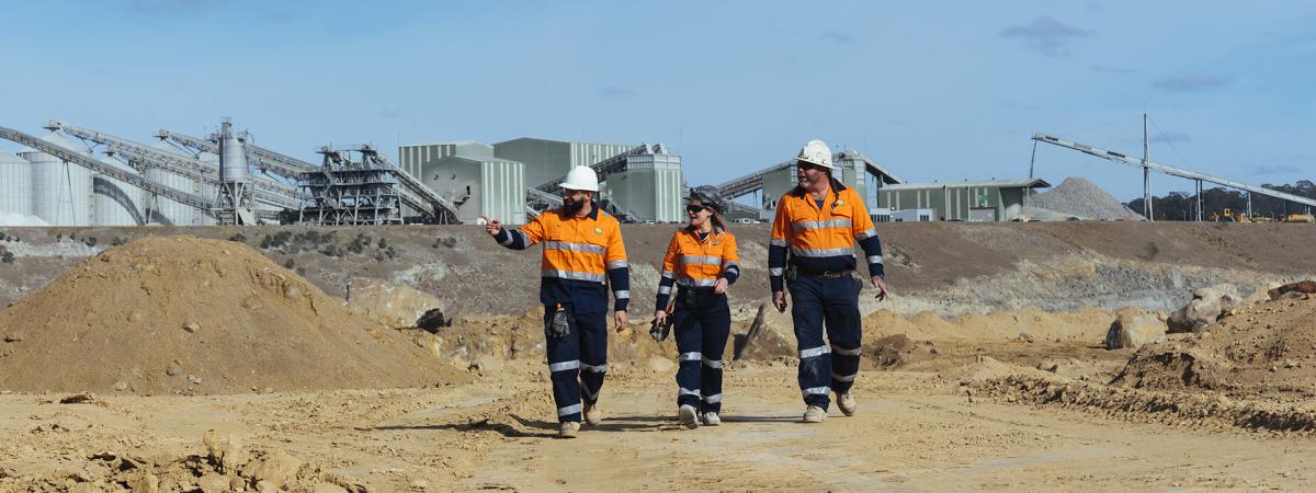 3 staff in orange PEE walking through mining site