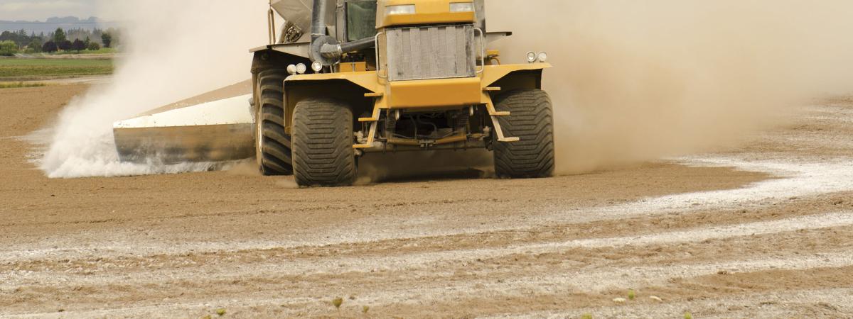Tractor on farm spreading aglime into field