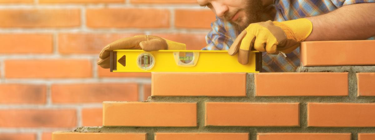 Builder leveling a brick wall