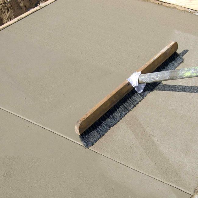 Concrete footpath being finished with a broom