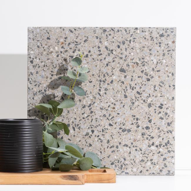 Slab of boralstone concrete in the colour Peppersand next to a black vase with green leaves