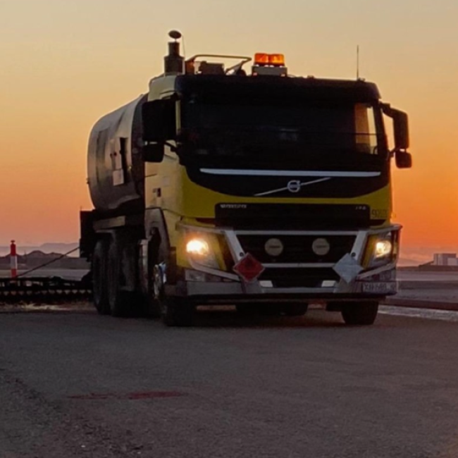Hot Spray Seal machine on asphalt pavement with sunset in background