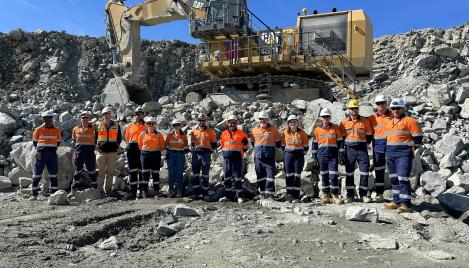 Boral team stand in quarry pit in from of CAT HME