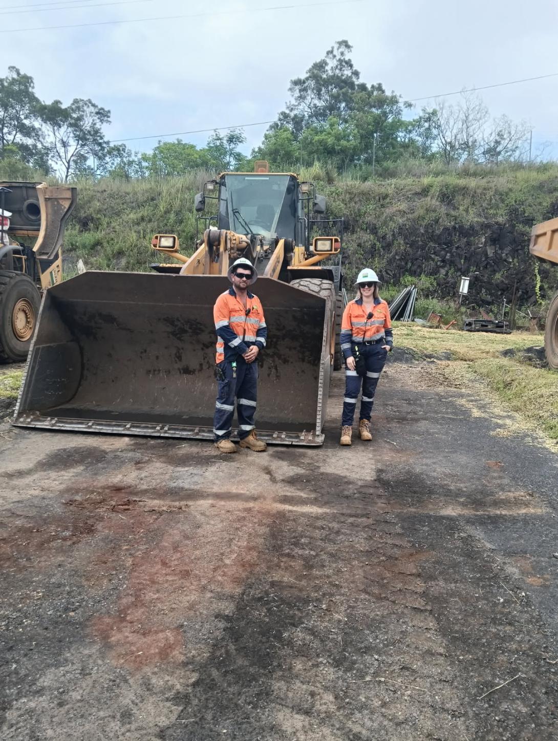 Hanna Moriconi and John West standing in front of an excavator
