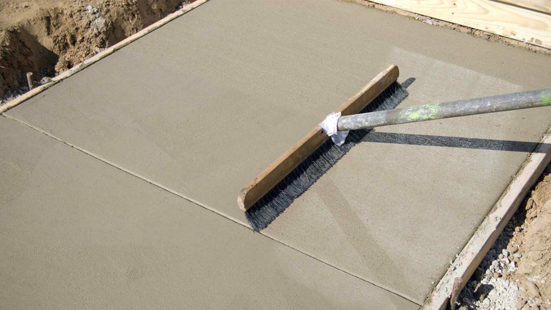 Concrete footpath being finished with a broom