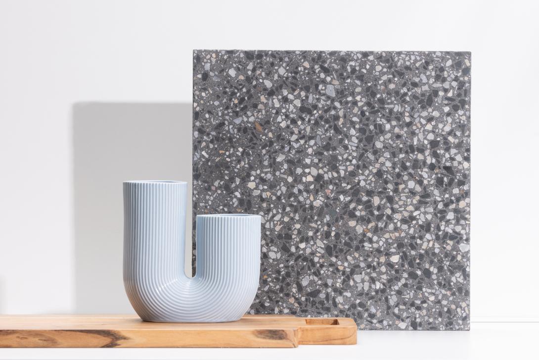 Slab of boralstone concrete in the colour Nightscape next to a blue vase
