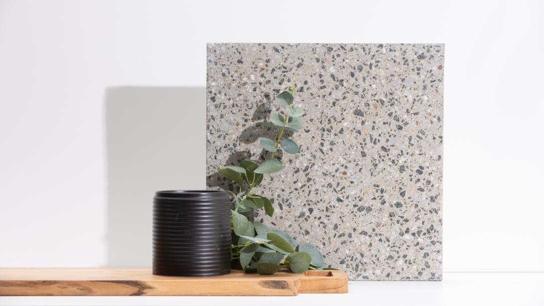 Slab of boralstone concrete in the colour Peppersand next to a black vase with green leaves