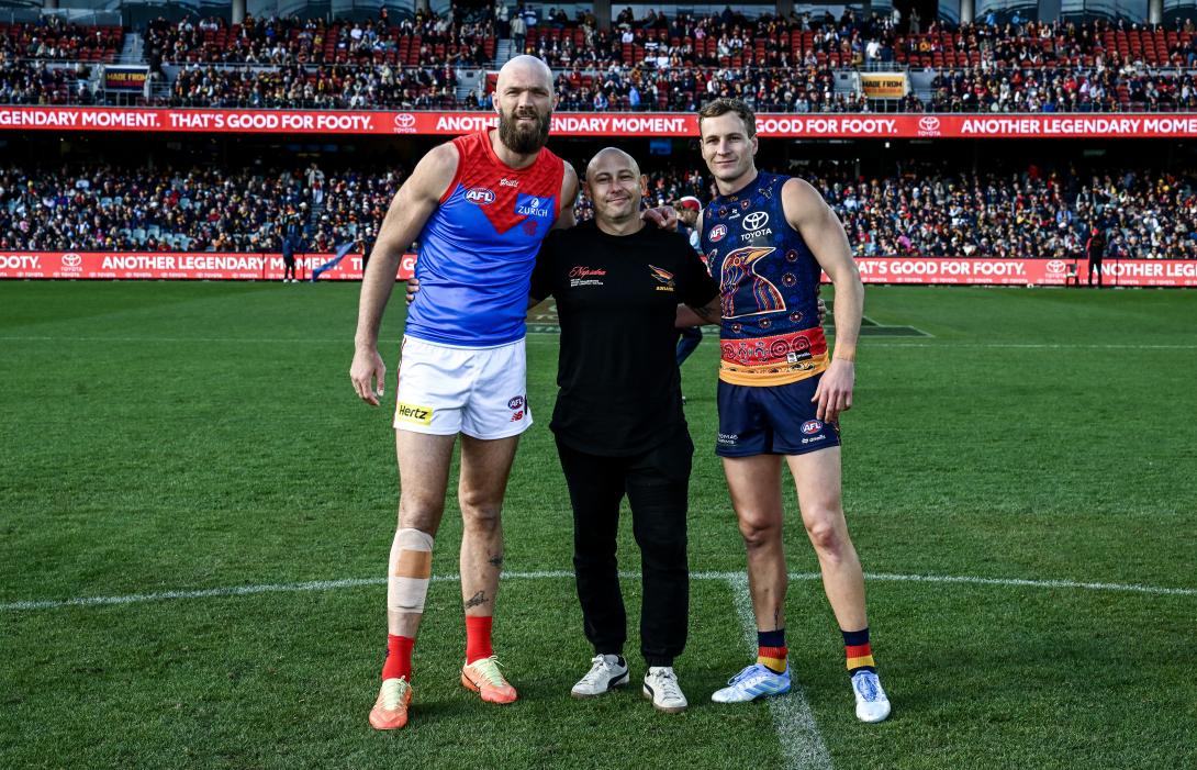 Boral's Nathan Hall on sports field in stadium with 2 professional AFL players