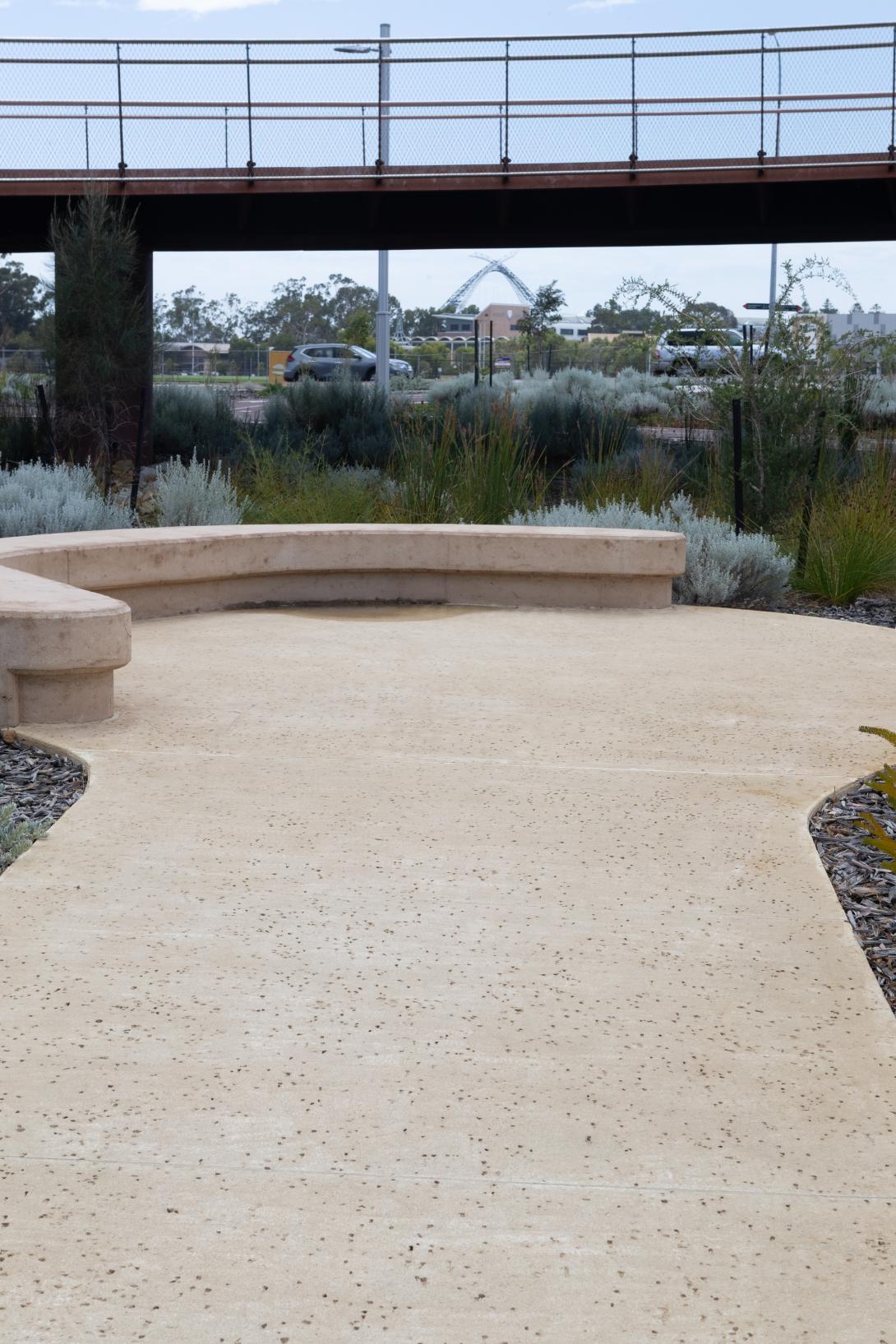 Coloured concrete pathway on Heirisson Island featuring Colori® Turmeric finish, connecting landscaped public spaces near Boorloo Bridge in Perth