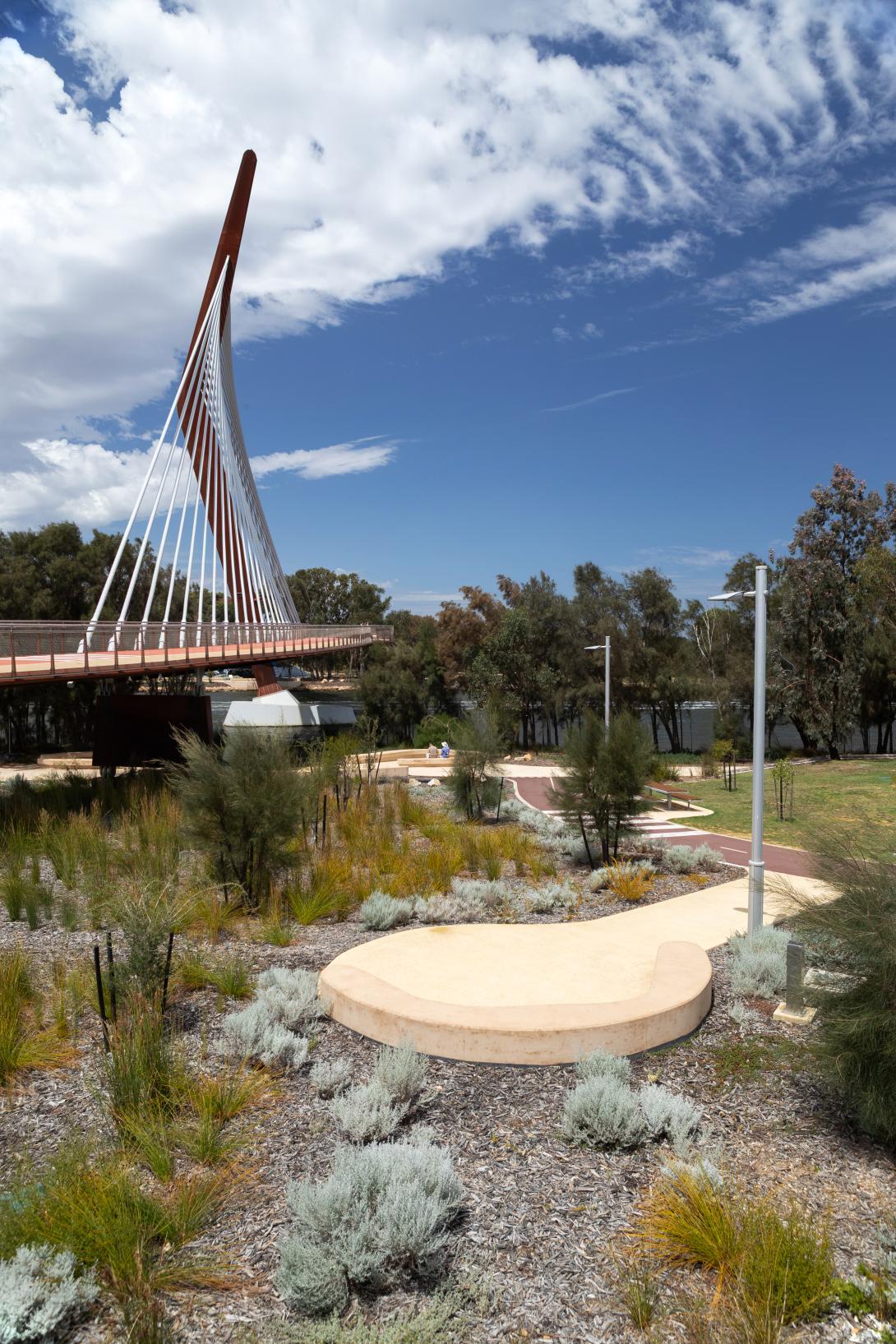 Coloured concrete pathway on Heirisson Island featuring Colori® Turmeric finish, connecting landscaped public spaces near Boorloo Bridge in Perth