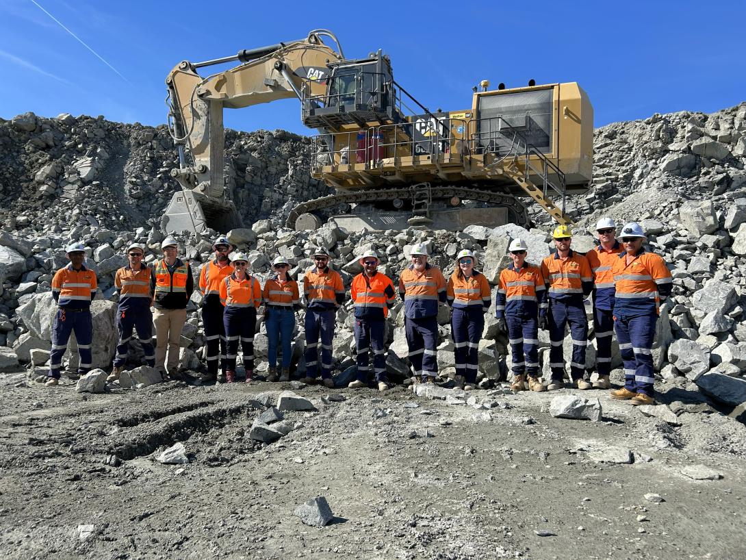 Boral team stand in quarry pit in from of CAT HME