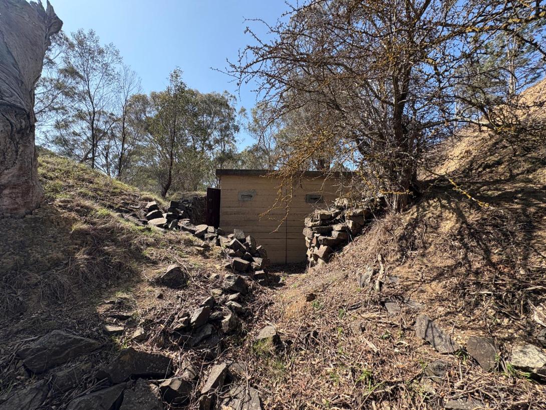 Historic explosives magazine at Coldstream Quarry surrounded by a dry-stone wall