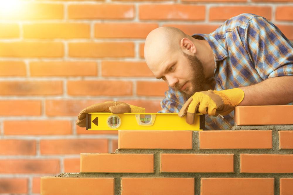Builder leveling a brick wall